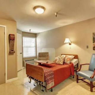 A cozy bedroom with a hospital bed and seating area.