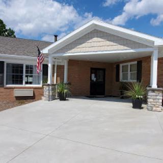 A welcoming entrance to a residential building, featuring decorative landscaping and an American flag.