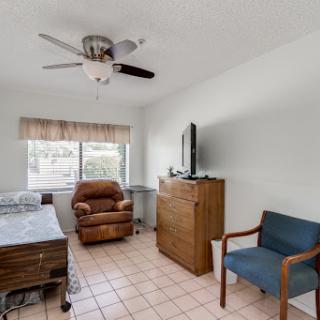 A cozy bedroom featuring a ceiling fan, comfortable seating, and natural light from the window.