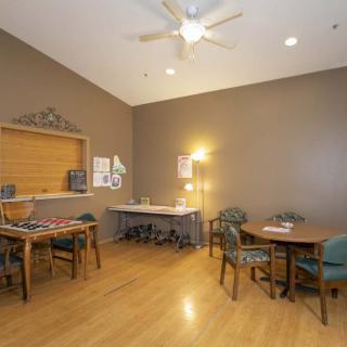 A room featuring tables and chairs, with a wooden floor and ceiling fan.