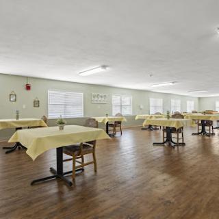 A spacious dining area featuring neatly arranged tables with yellow tablecloths.