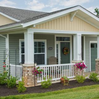 A charming cottage-style house with a front porch and well-maintained landscaping.