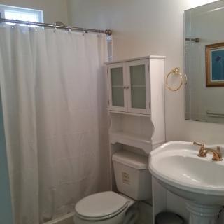 A small bathroom with a white shower curtain, sink, and toilet.