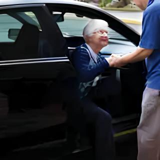 An elderly person being assisted out of a car.
