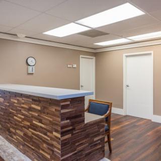 A modern reception area featuring wooden accents, a clock on the wall, and a cozy waiting space.