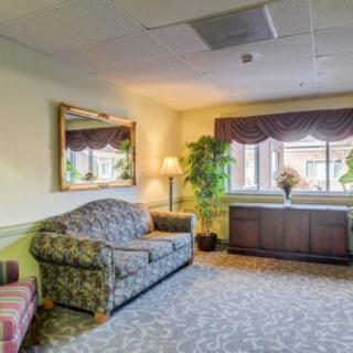A cozy living room with a patterned sofa, mirror, and a large window with curtains.