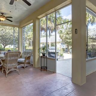 A bright sunroom featuring wicker furniture, large glass windows, and ample natural light.