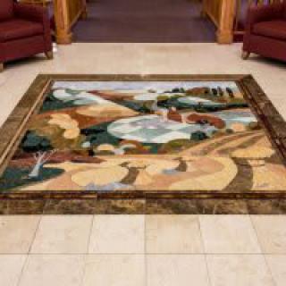 An abstract art rug displayed on a tiled floor in an interior setting.