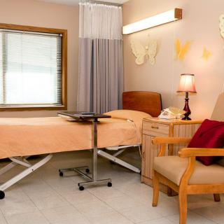 A cozy hospital room with a bed, chair, and soft lighting.
