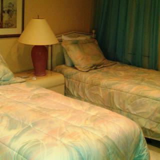 A cozy bedroom with two twin beds, a lamp, and curtains.