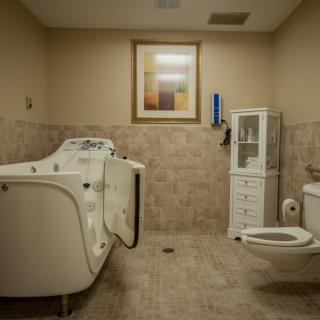A spacious bathroom with an accessible bathtub and safety features designed for healthcare facilities.