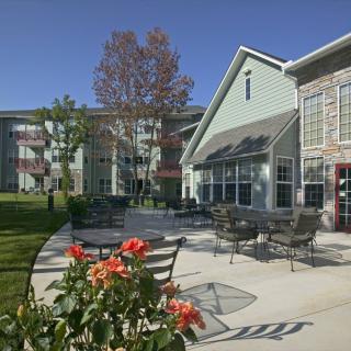 A serene outdoor patio area with tables and chairs, surrounded by a building and vibrant flowers.