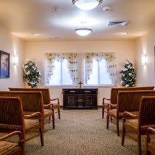 A small chapel interior with seating and decorative plants.