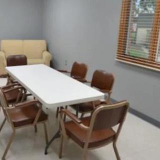 A meeting room with a white table, several chairs, and a sofa by the window.