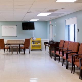An empty waiting room with rows of chairs, a television, and a whiteboard on the wall.