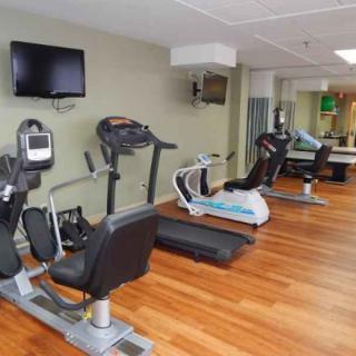 A well-equipped gym featuring treadmills and stationary bikes on a wooden floor.