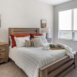 A modern bedroom with wooden furnishings and a cozy atmosphere, filled with natural light.