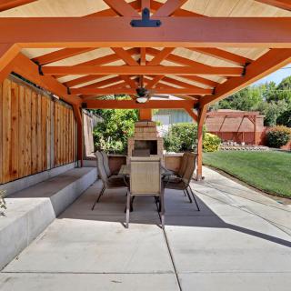 A backyard patio with a pergola, furnished with a table and chairs for outdoor dining.