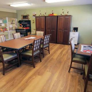 A well-organized dining area featuring wooden tables and chairs, with ample storage cabinets and a wooden floor.