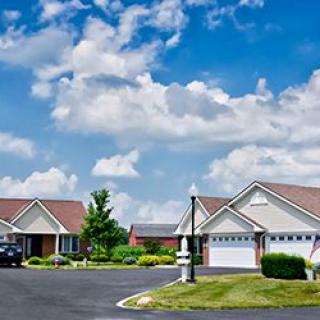 A quiet suburban neighborhood with well-maintained houses under a partly cloudy sky.