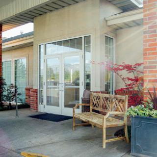 A welcoming entrance with a wooden bench and vibrant plants.