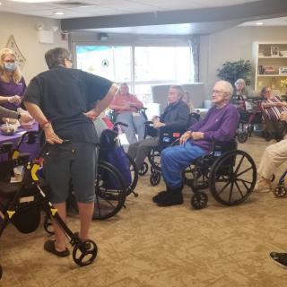 A group of elderly individuals in wheelchairs gathered together in a nursing home setting.