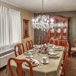 An elegant dining room with a chandelier and a table set for dinner.