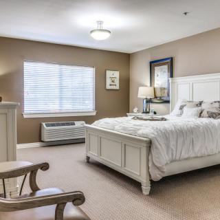 A cozy and elegantly furnished bedroom with a large bed, soft carpeting, and ample natural light.