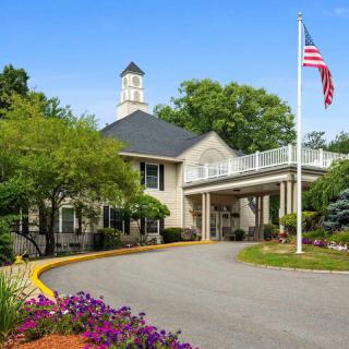 A welcoming building with an American flag, surrounded by lush landscaping and vibrant flowers.