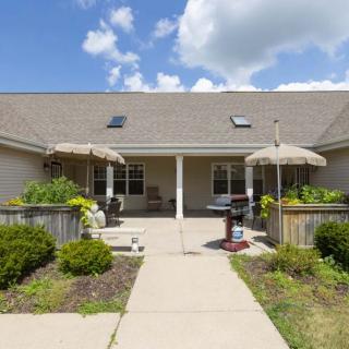 A residential house with a patio and garden, featuring outdoor umbrellas under a partly cloudy sky.