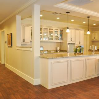 A modern open-layout kitchen with white cabinets, pendant lighting, and a spacious countertop.