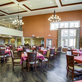 A spacious dining hall with elegant furnishings and large windows.