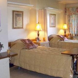 A well-lit hospital room featuring two beds with golden bedding and comforting decor.