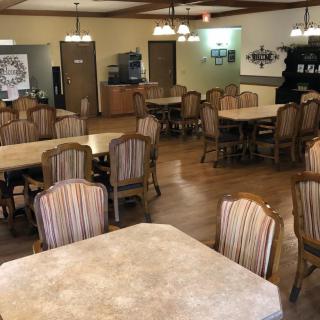 An empty dining area with neatly arranged tables and chairs, featuring a warm interior design.