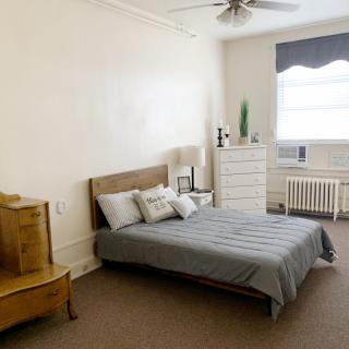 A minimalist bedroom with a bed, dresser, and window.