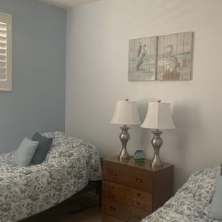 A cozy bedroom with twin beds, decorative pillows, and a nightstand featuring two lamps.