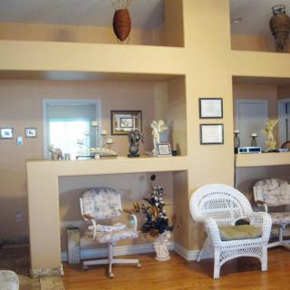 A cozy living room with wicker chairs and decorative items on shelves.