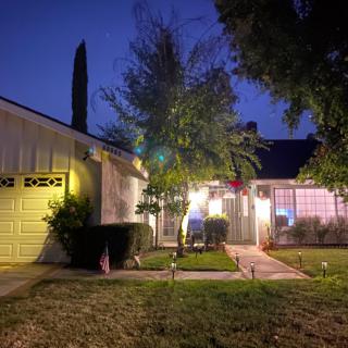 A cozy house illuminated at night with a well-lit pathway leading to the entrance.