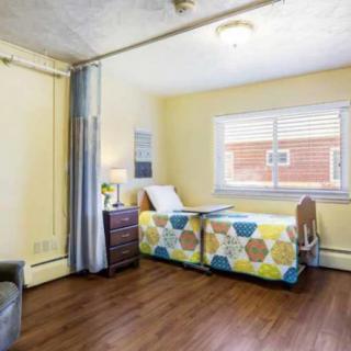 A cozy hospital room with a single bed and wooden flooring.
