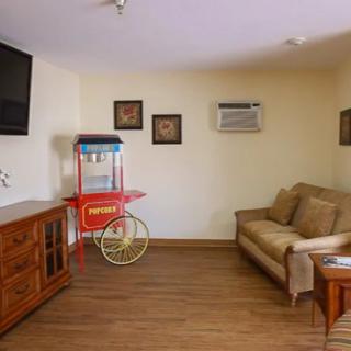 A cozy living room with a sofa, popcorn machine, and wall-mounted TV.