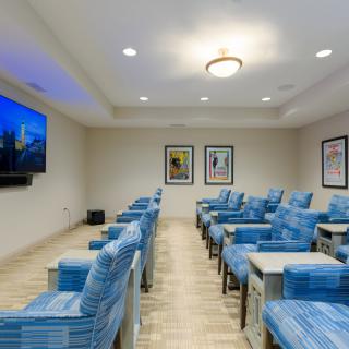 A cozy theater room with blue seating and a large screen.