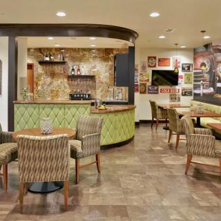 A cozy restaurant interior featuring a seating area with tables and chairs, bar section, and decorative elements.