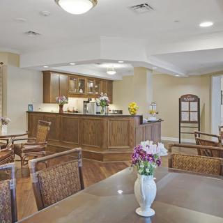 A cozy cafe interior with a wooden counter and comfortable seating, adorned with flowers.