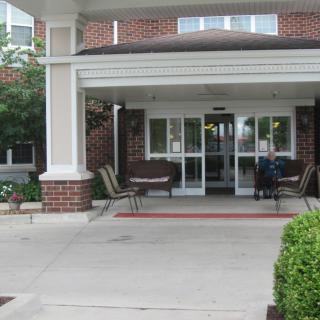 Entrance of a brick building with benches and plants.