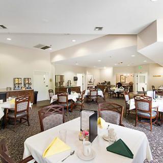 A well-lit dining room with multiple tables and chairs, set up for guests.