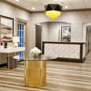 A modern reception area featuring a glass table with flowers and artwork adorning the walls.