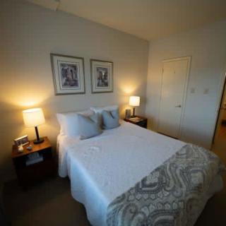 A cozy bedroom with a neatly made bed, flanked by two nightstands and lamps.