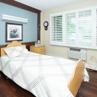 A cozy and minimalist bedroom featuring a single bed, wooden flooring, and natural light.