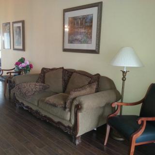 A cozy living room with a classic sofa, a standing lamp, and framed artwork on the wall.
