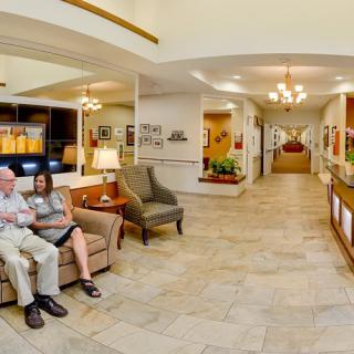 A spacious lobby with seating area and reception desk, featuring chandeliers and decor.